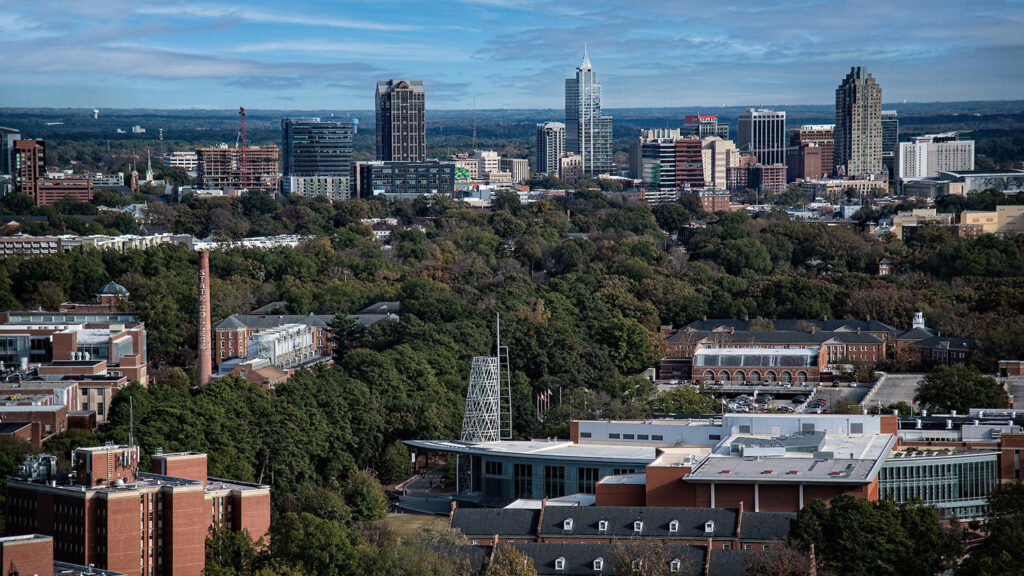 An aerial photo of the Talley Student union with the downtown Raleigh skyline in the background. 